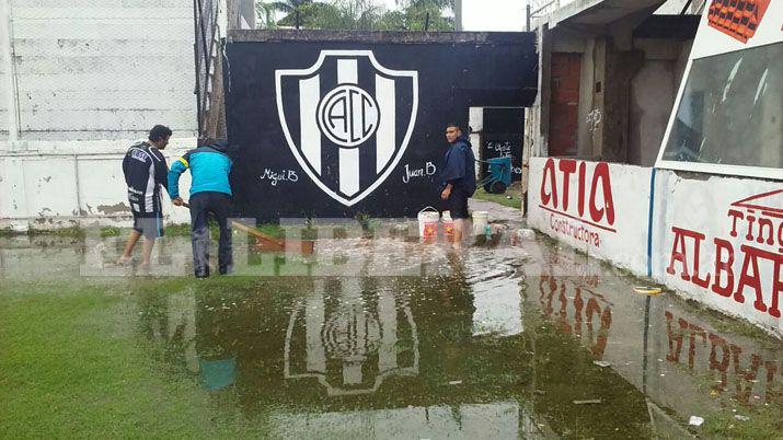 Hinchas solidarios del Ferro sacan el agua de la cancha