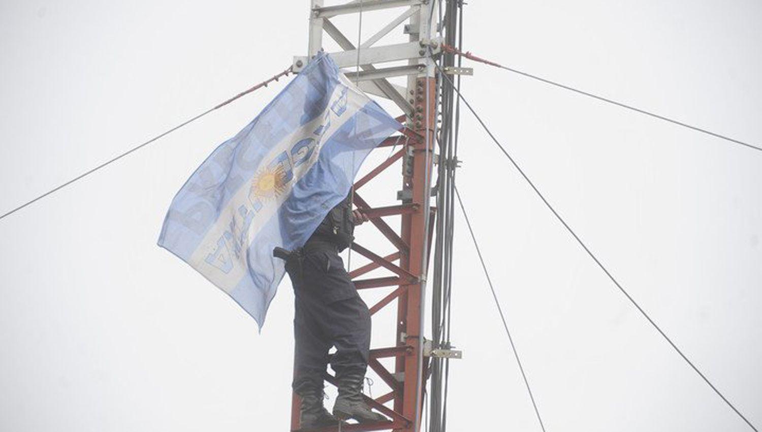 Tensioacuten- Un policiacutea se trepoacute a una antena en sentildeal de protesta
