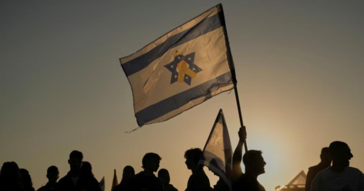 Personas sostienen banderas israelíes antes de que comenzara la liberación de rehenes el lunes (Foto- APLeo Correa)
