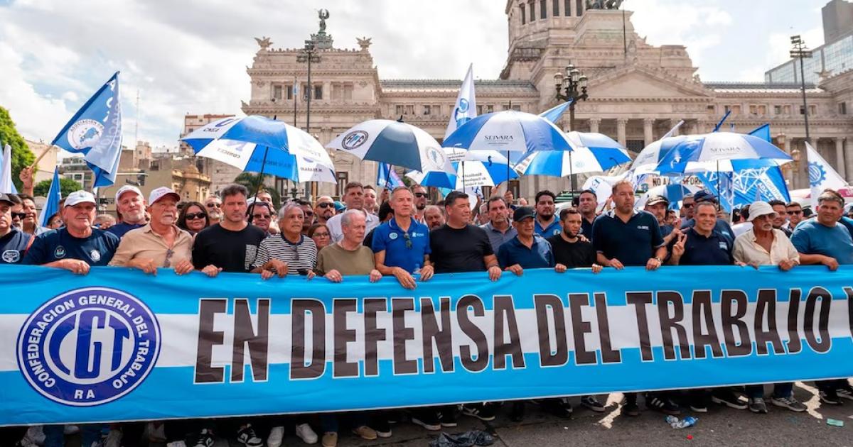 Miembros de la columna de la CGT marchan frente al Congreso en Buenos Aires portando una pancarta que dice EN DEFENSA DEL TRABAJO durante la movilización contra la reforma laboral