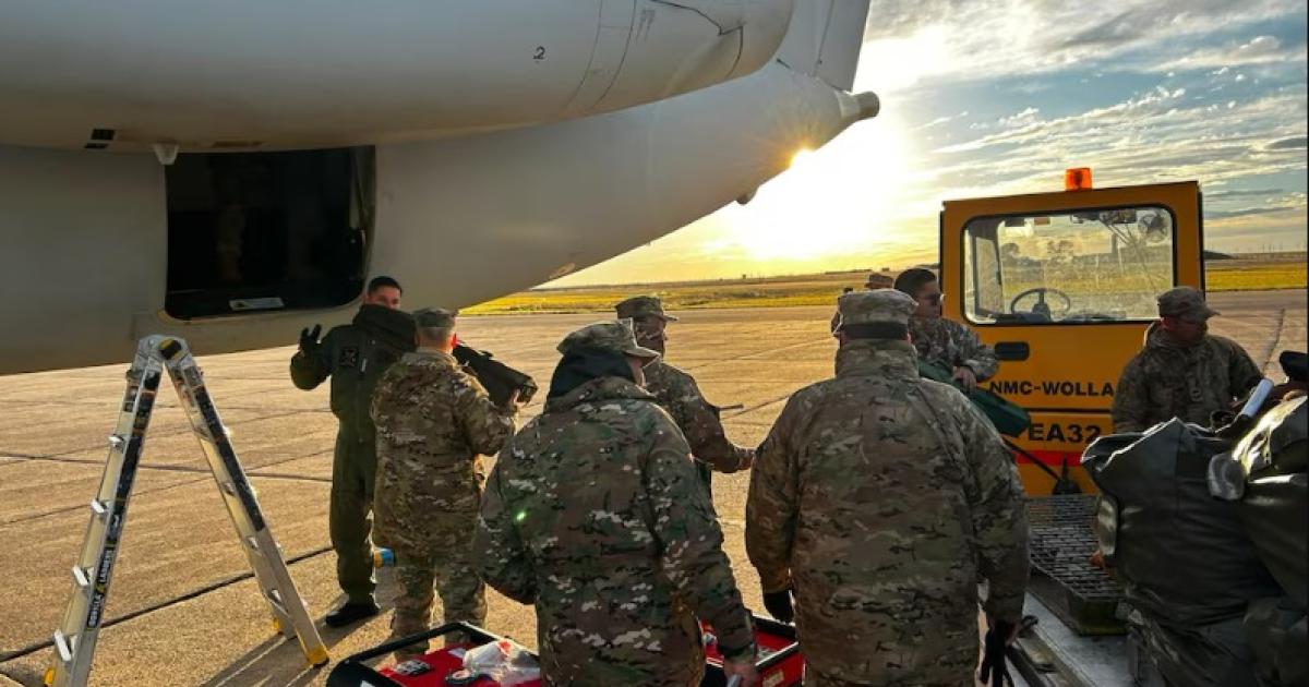Personal de las Fuerzas Armadas de Argentina trabaja junto a un avión de carga al atardecer para una operación de transporte